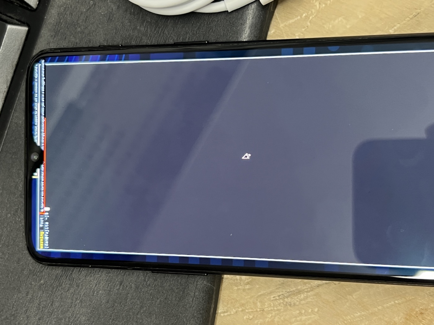 The phone held in hand showing the Omarchy wallpaper